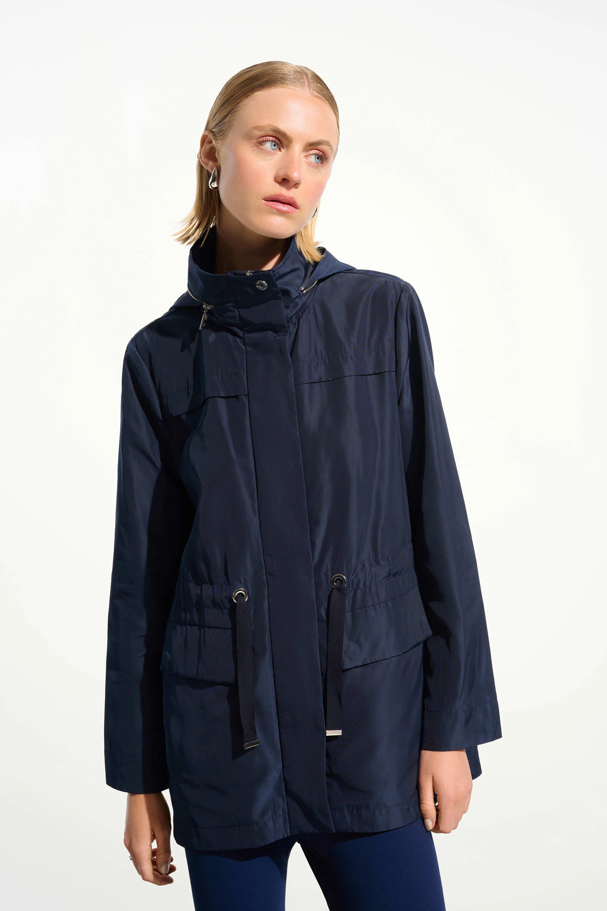 Woman wearing a navy blue raincoat on a white background