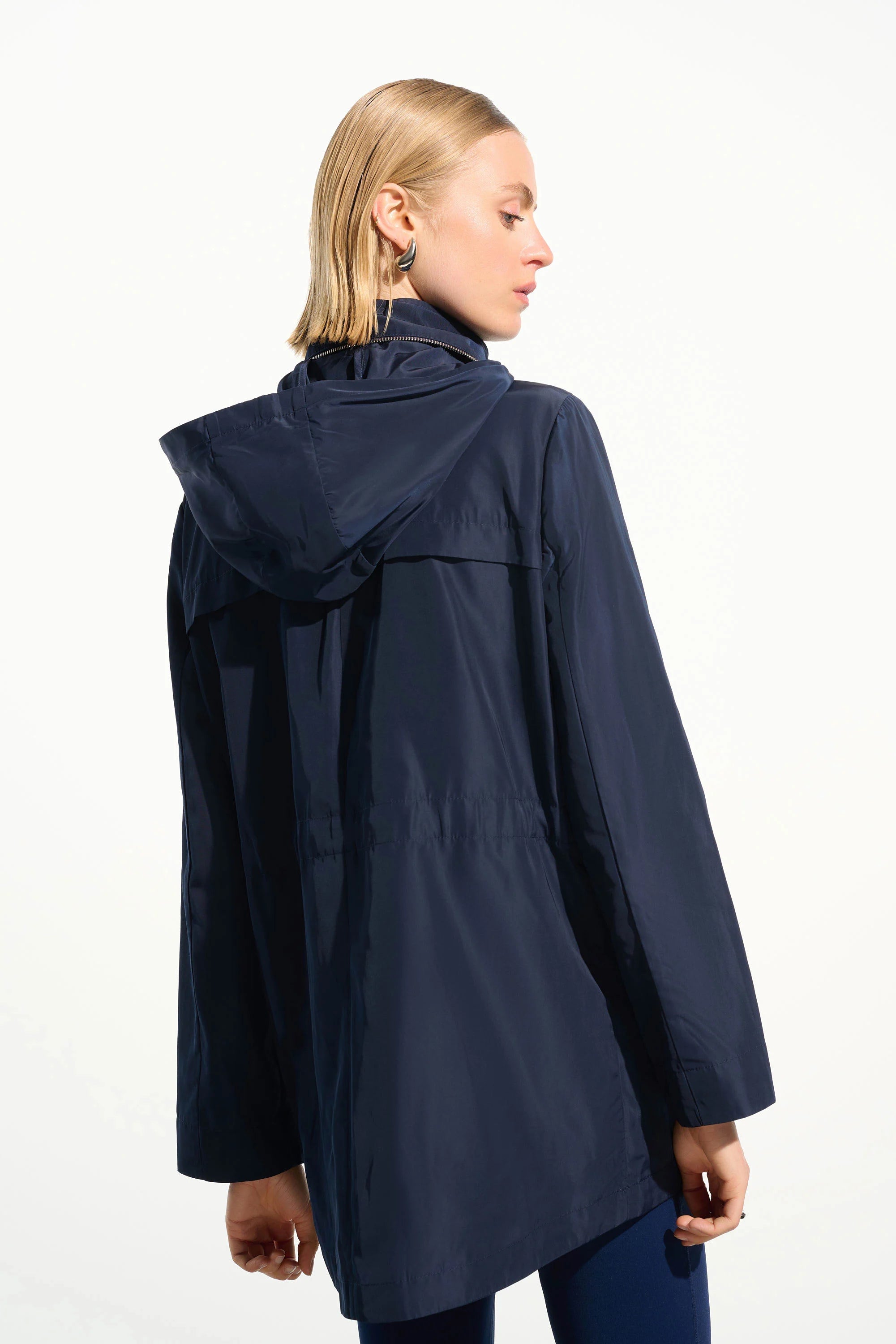 Woman wearing a navy raincoat on a white background