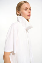 Person wearing a white high-neck outfit on a plain background