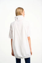 Person wearing a white shirt with a high collar on a white background