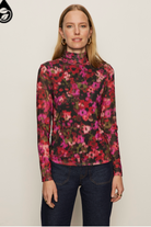 Woman wearing a floral long-sleeve top against a plain background