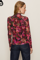 Woman wearing a floral long-sleeve top against a plain background