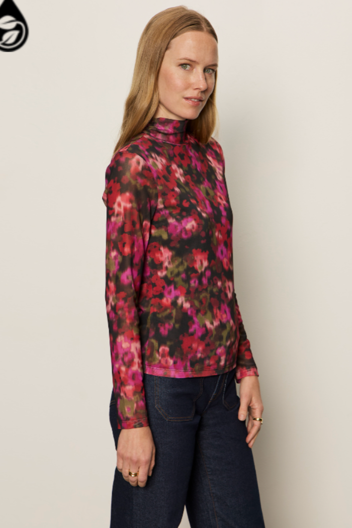 Woman wearing a floral long-sleeve top against a plain background