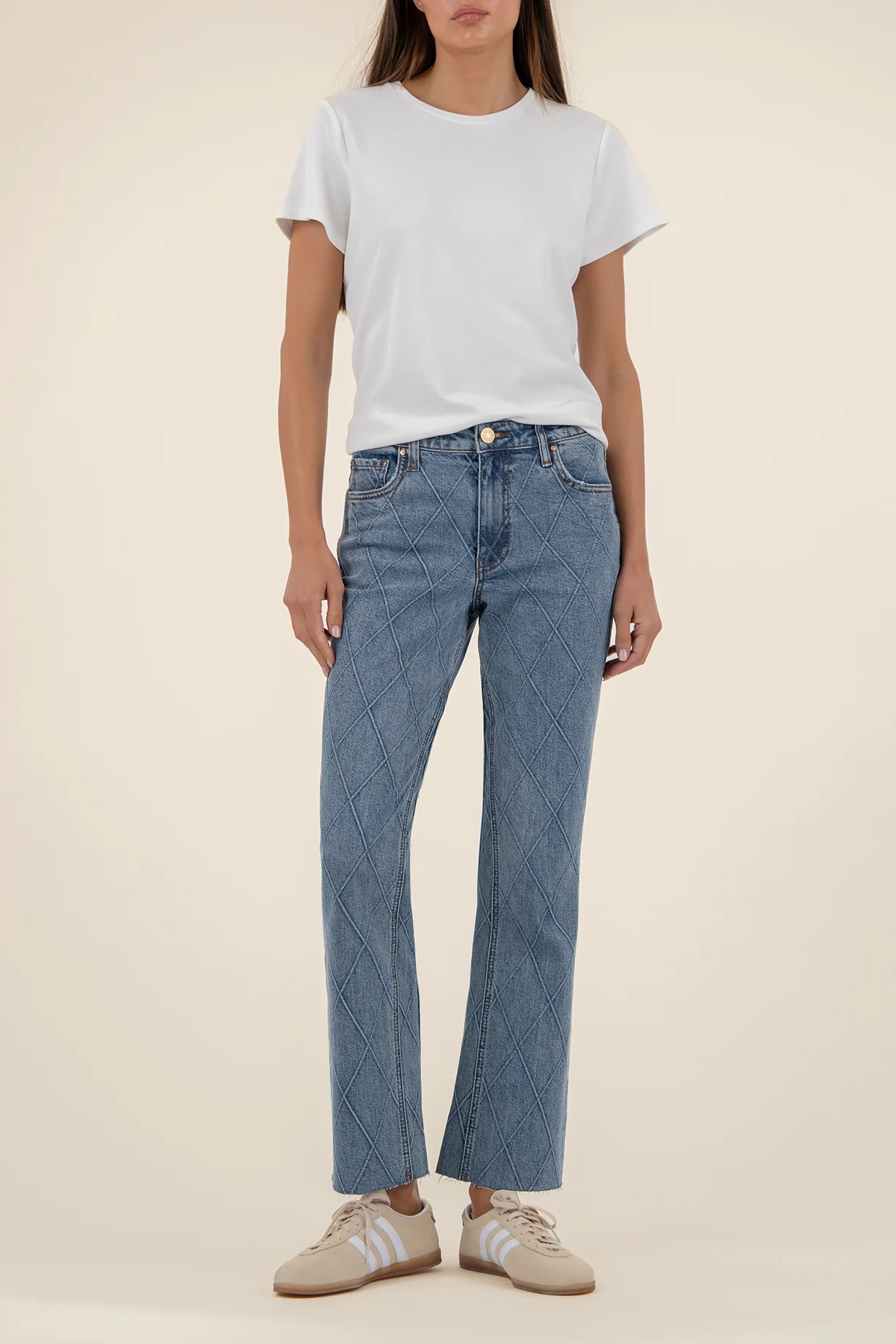 Person wearing a white t-shirt and blue jeans on a beige background
