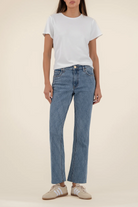 Person wearing a white t-shirt and blue jeans on a beige background