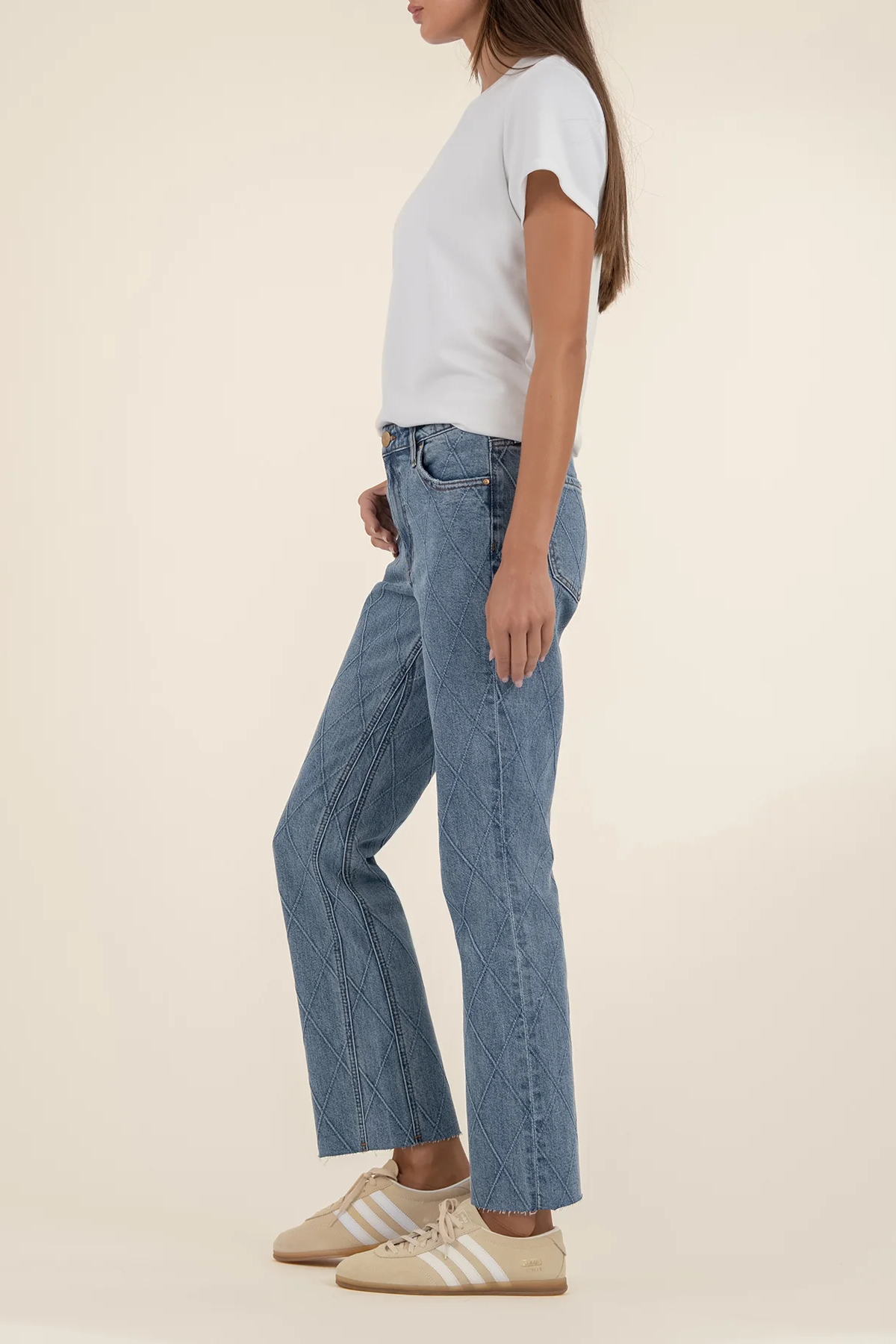 Person wearing blue jeans and a white t-shirt on a beige background