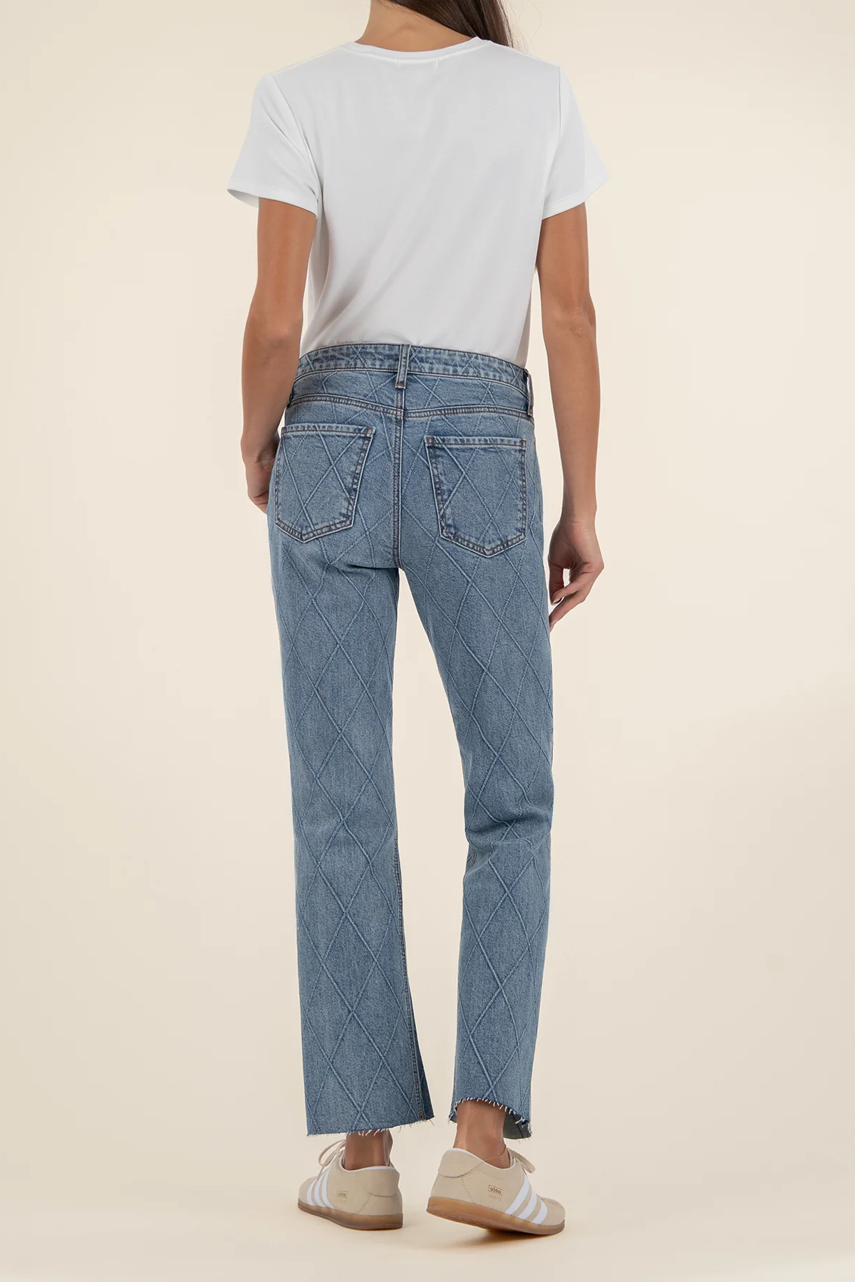 Person wearing blue jeans and a white t-shirt on a beige background