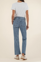 Person wearing blue jeans and a white t-shirt on a beige background