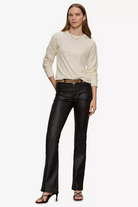 Woman wearing a cream sweater and black leather pants on a white background