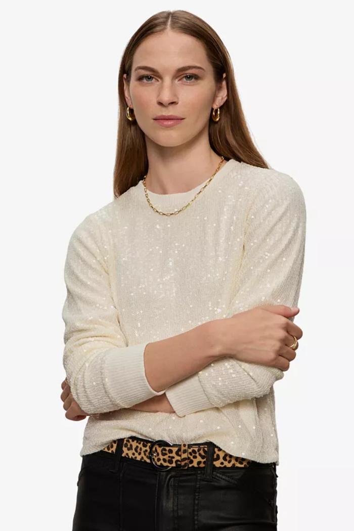 Woman wearing a cream sweater with leopard print trim on a white background