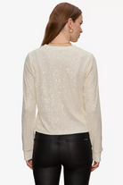 Woman wearing a beige sweater with subtle pattern on a white background