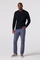 Man wearing a black sweater and gray pants on a white background