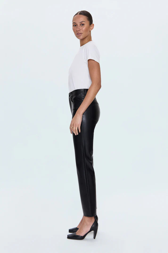 Woman wearing a white top and black leather pants on a light blue background