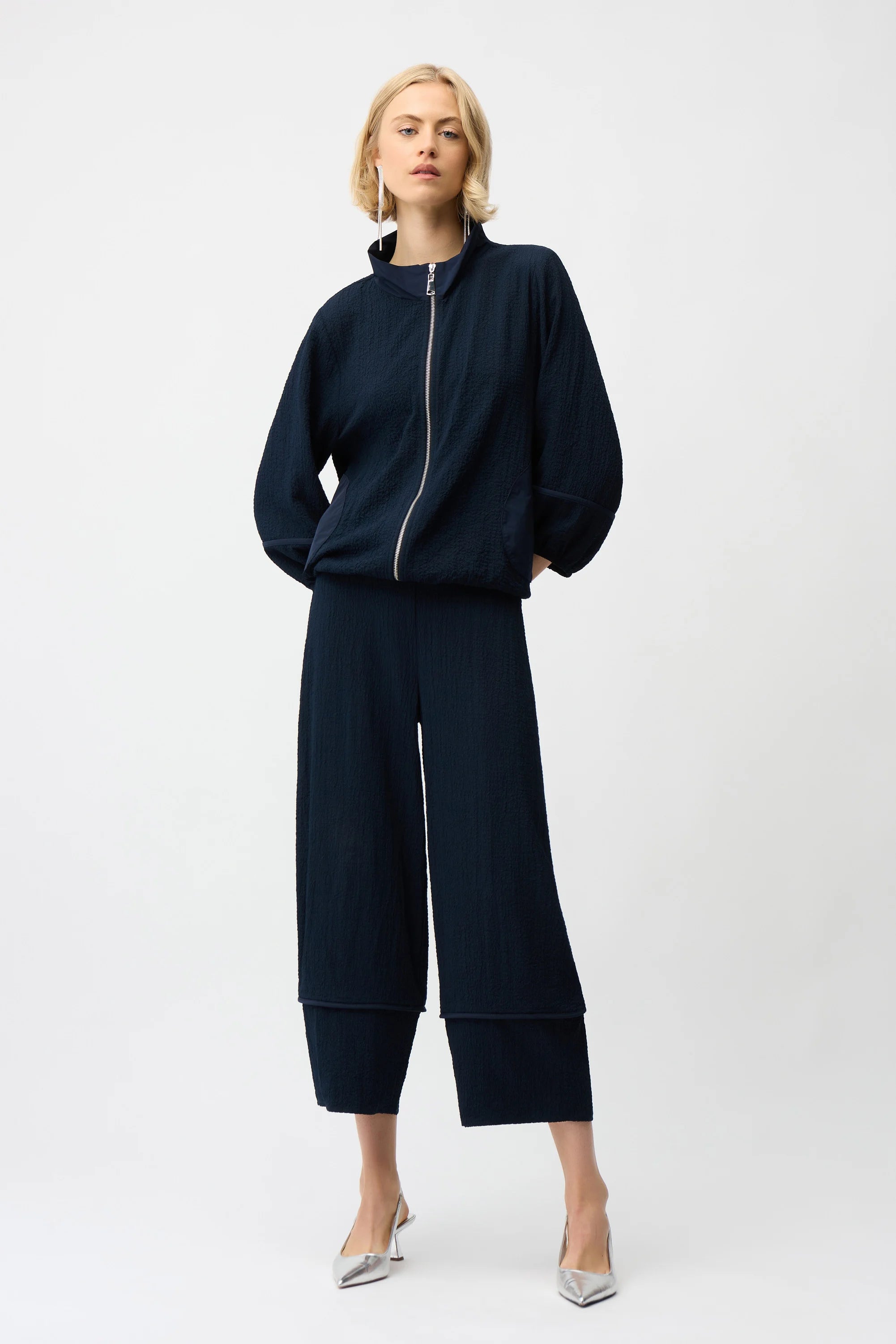 Person wearing a navy blue outfit with wide-leg pants on a white background
