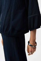Person wearing a dark textured outfit with a white background