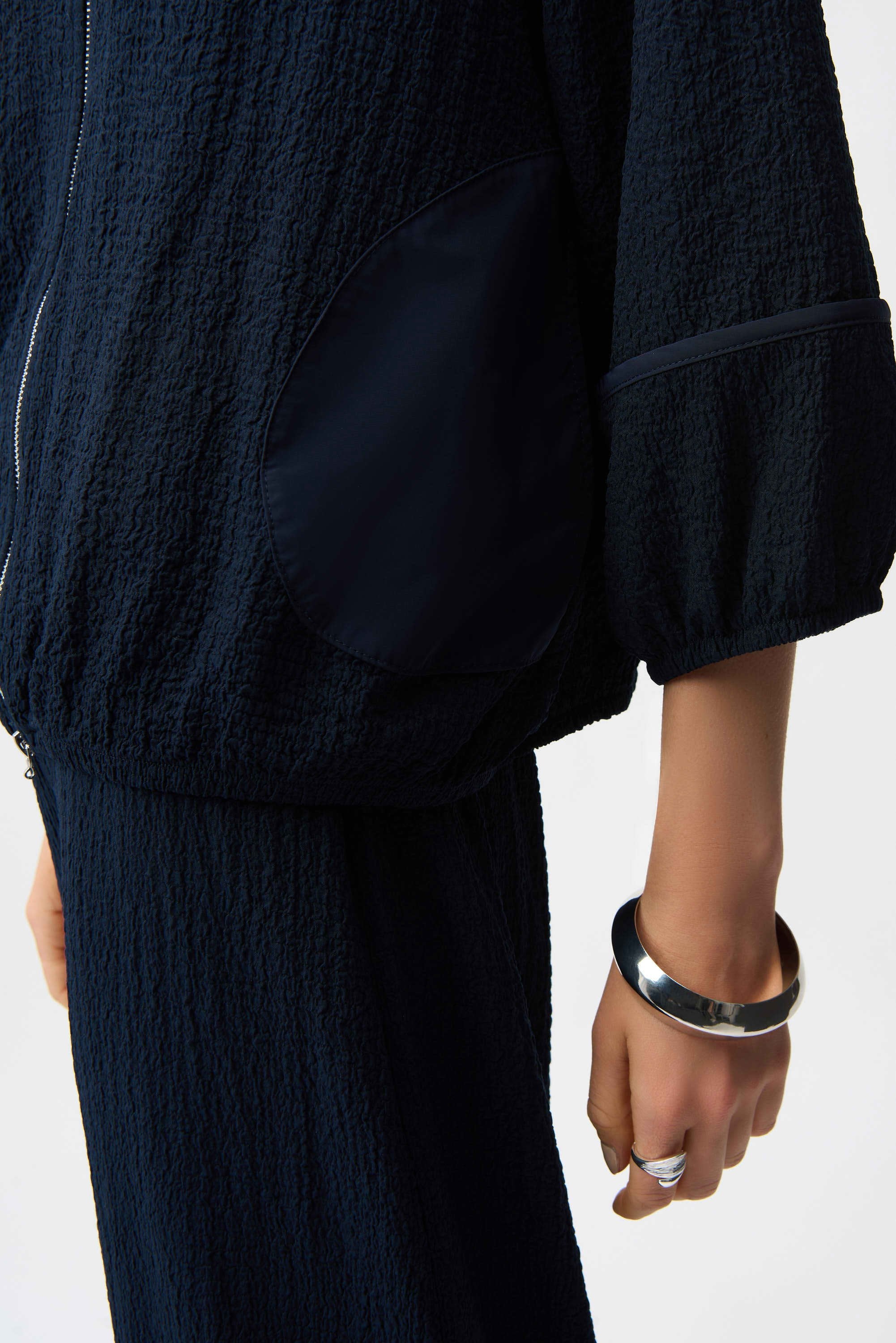 Person wearing a dark textured outfit with a white background