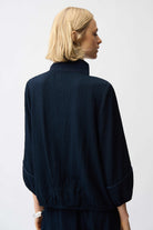 Person wearing a dark blue jacket on a plain background