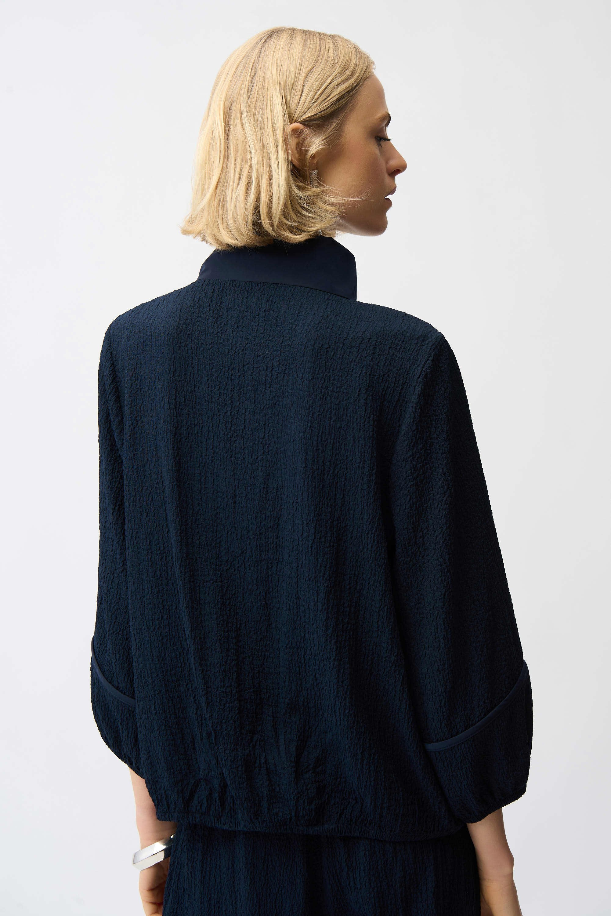 Person wearing a dark blue jacket on a plain background