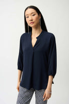 Woman wearing a navy blue blouse and patterned pants on a white background
