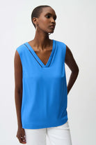 Woman wearing a blue sleeveless top against a white background