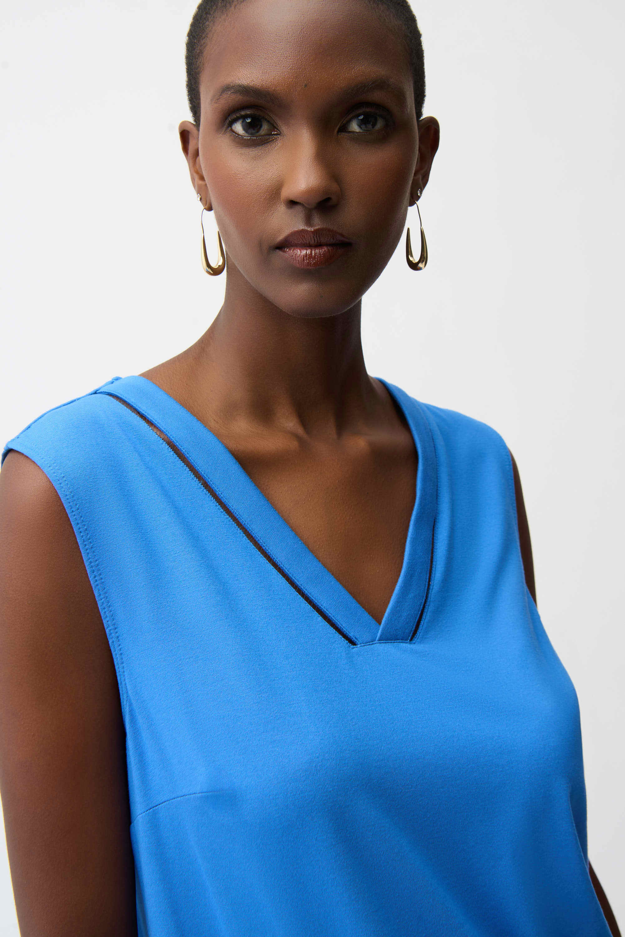 Woman wearing a blue sleeveless top against a plain background