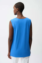 Person wearing a blue sleeveless top on a white background
