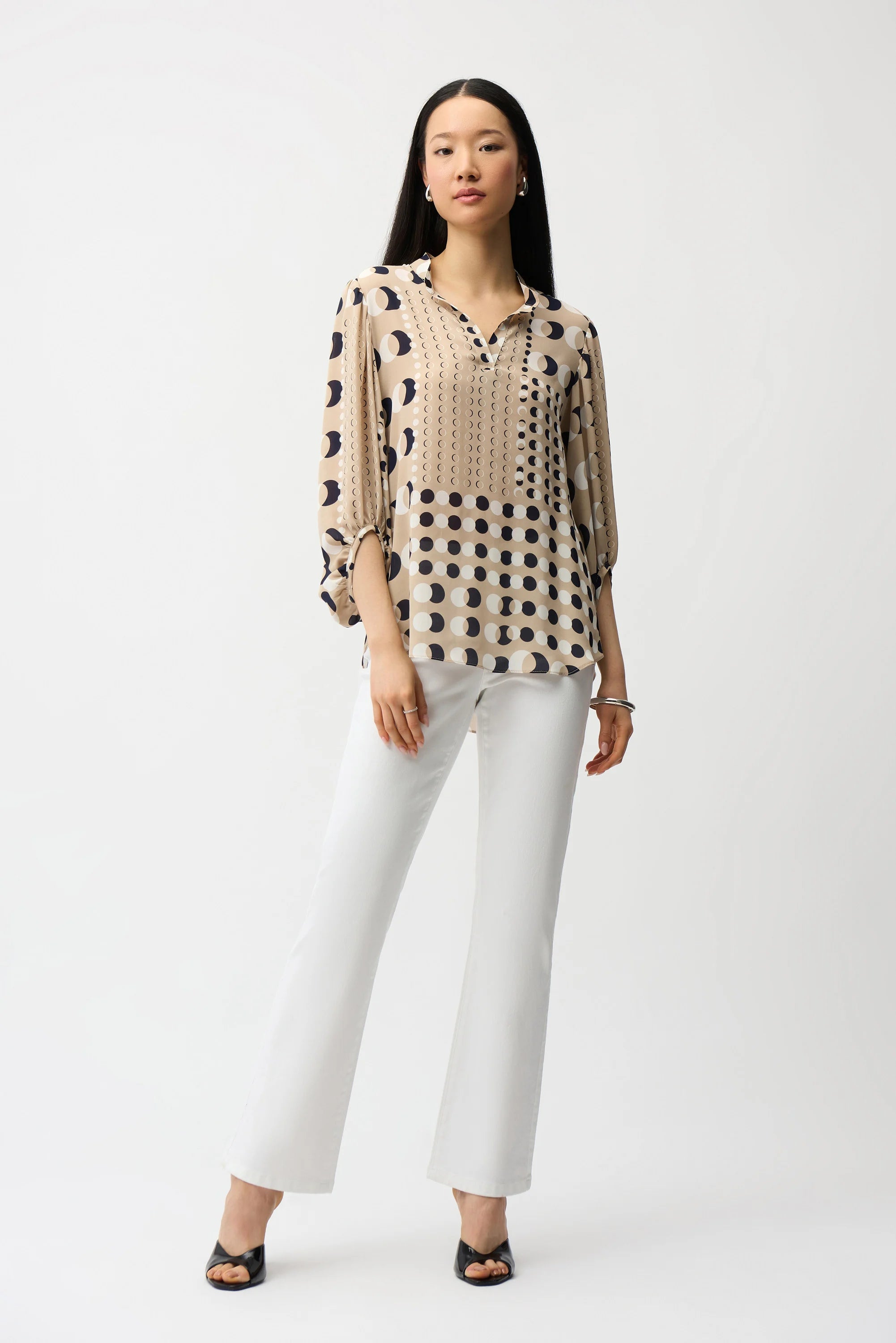 Woman wearing a patterned blouse and white pants on a white background