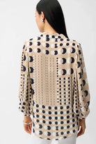 Woman wearing a beige blouse with black geometric pattern on a white background