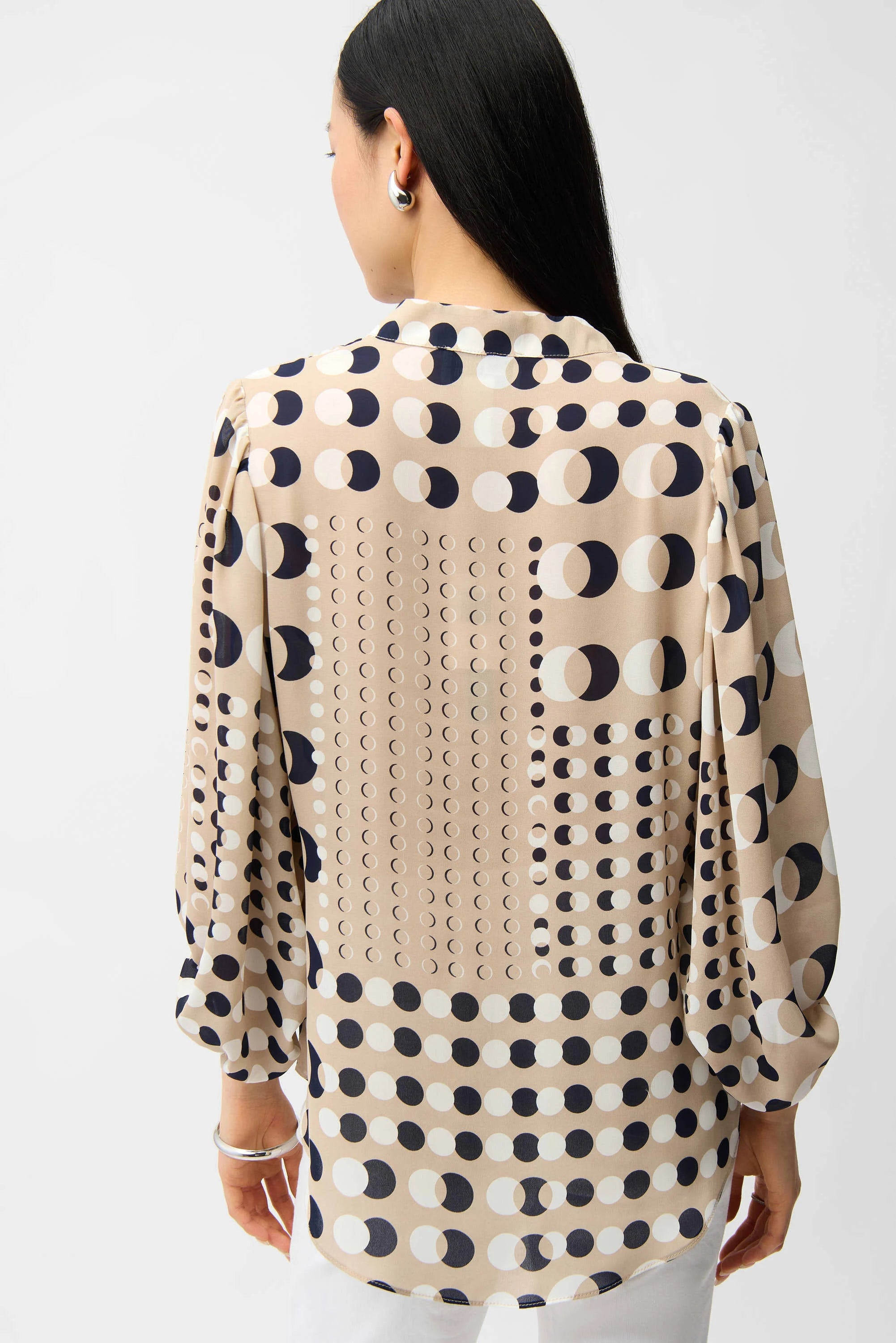 Woman wearing a beige blouse with black geometric pattern on a white background