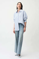 Woman wearing a light blue striped shirt and jeans on a white background