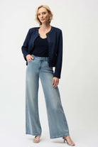 Woman wearing a navy jacket and light blue jeans on a white background