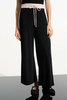 Black wide-leg pants with a beige belt on a white background