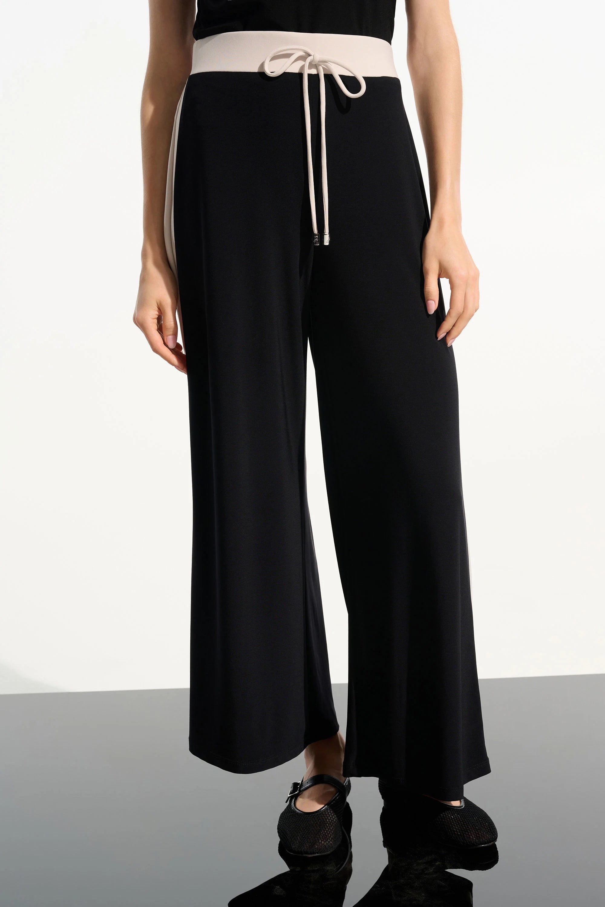 Black wide-leg pants with a beige belt on a white background