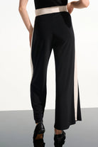 Black pants with a white stripe worn by a person on a plain background