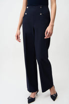 Black pants with button details worn by a person on a white background