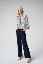 Woman wearing a black and white patterned jacket and navy pants on a white background