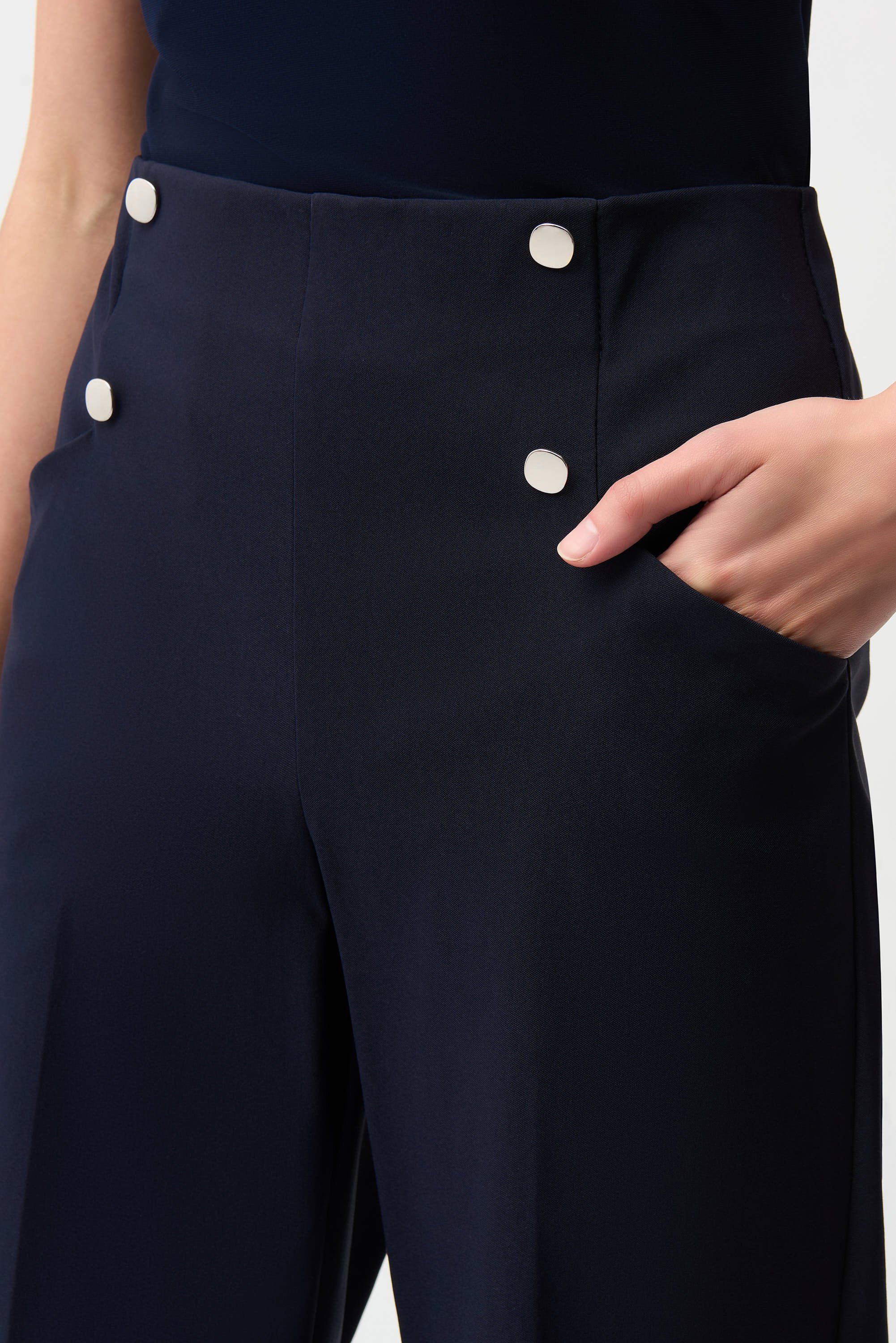 Navy blue pants with white buttons on a plain background