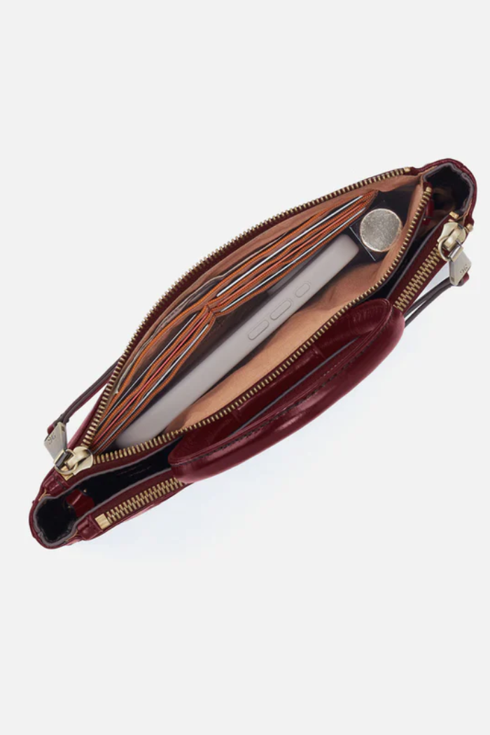 Open red leather handbag with gold zipper on a white background