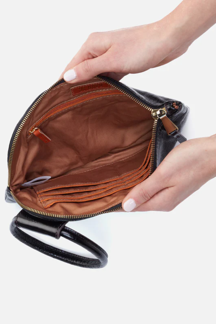 Hand holding an open black leather handbag with a white background