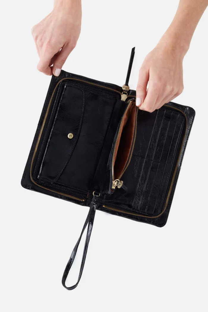 Black clutch bag with a strap held by hands on a white background