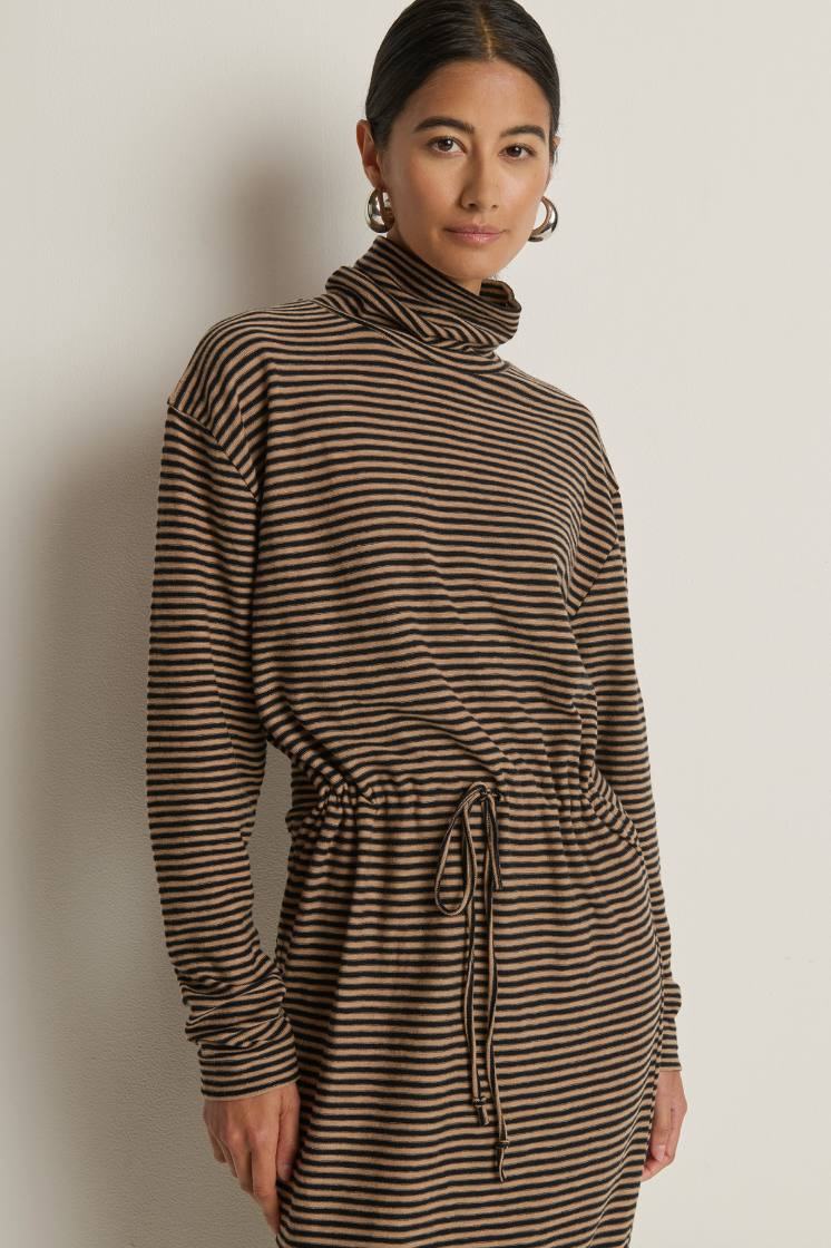 Woman wearing a brown and black striped dress against a plain background