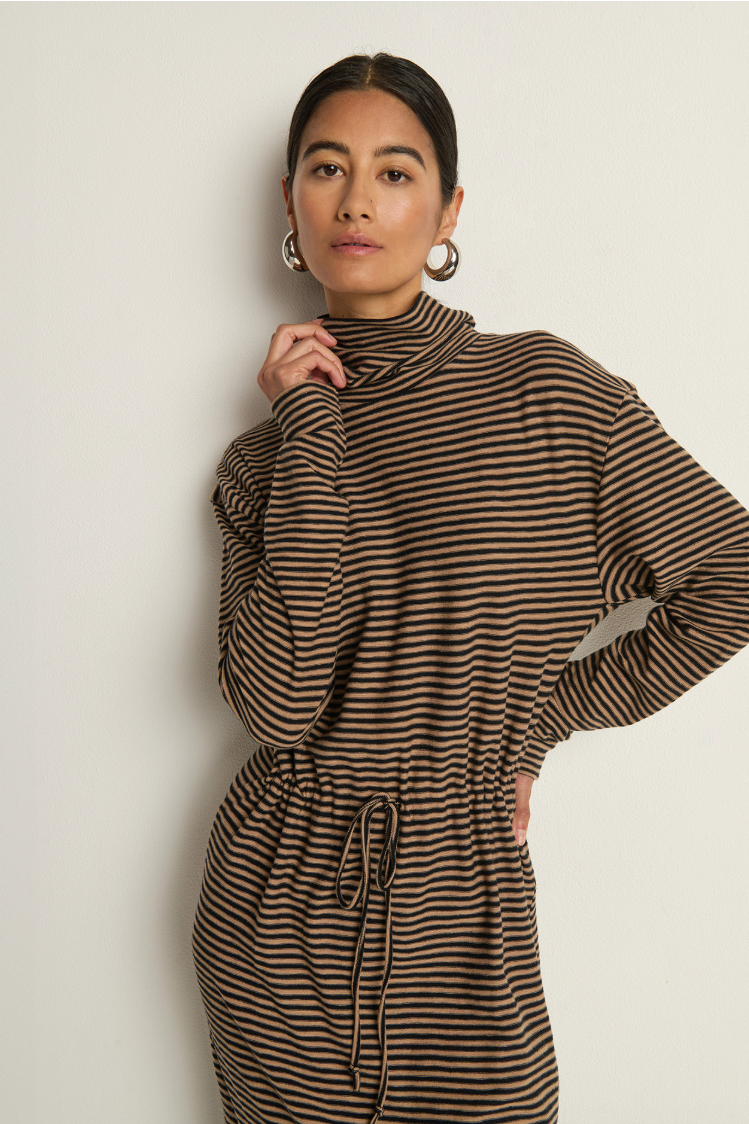 Woman wearing a brown and black striped dress against a plain background