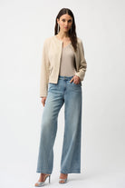 Woman wearing a beige blazer, beige top, and light blue jeans on a white background