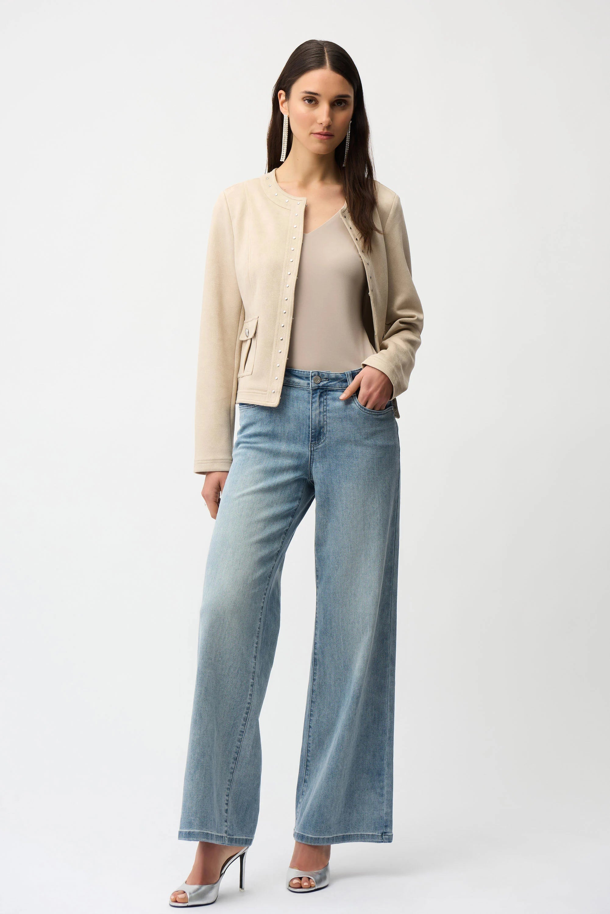 Woman wearing a beige blazer, beige top, and light blue jeans on a white background