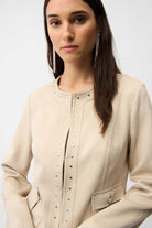 Woman wearing a beige coat with pearl embellishments on a white background