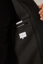 Close-up of a dark gray jacket with a brand label on the chest pocket.