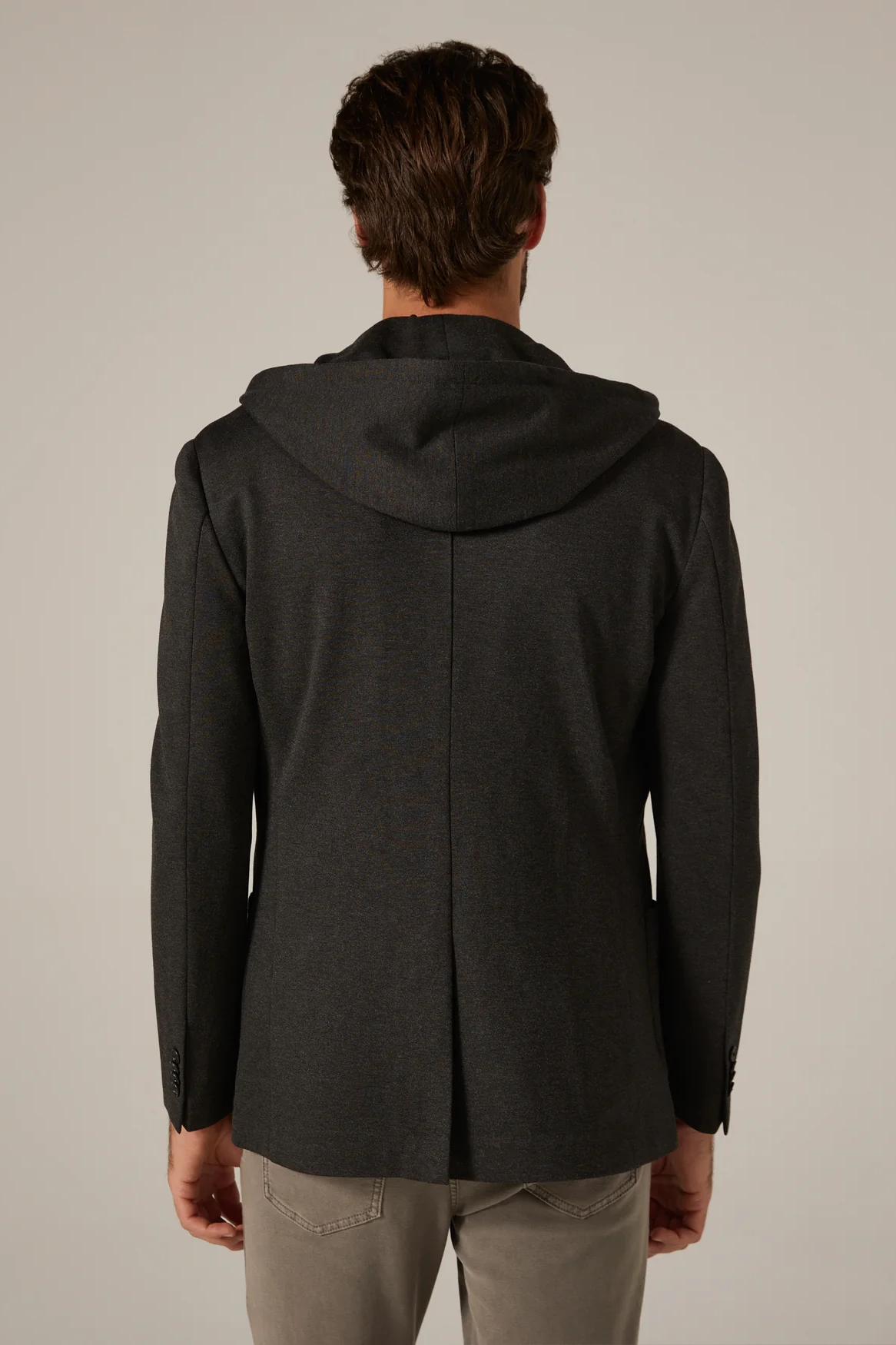 Man wearing a black hooded jacket on a plain background