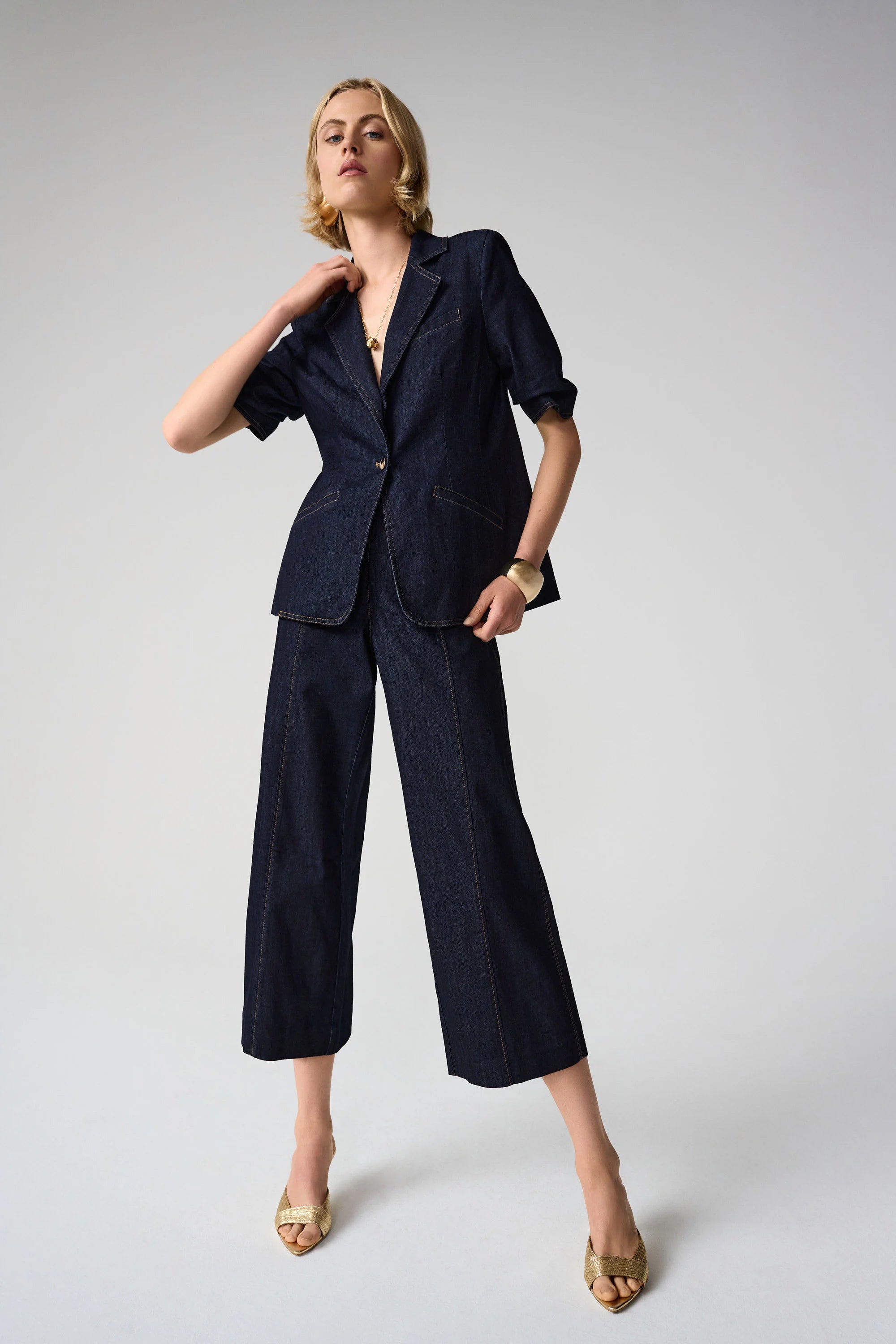 Woman wearing a navy blue suit with wide-leg pants on a light gray background