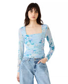 Woman wearing a floral long-sleeve top and jeans on a white background