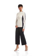 Woman wearing a two-tone sweater and black pants on a white background
